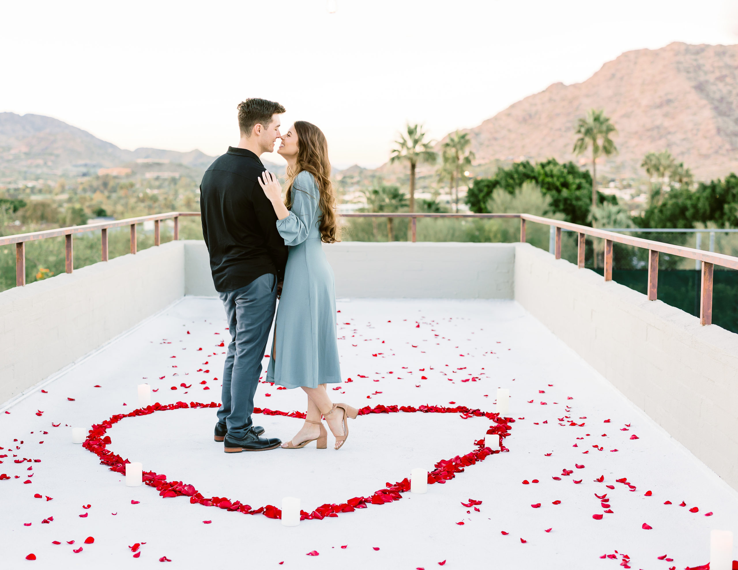 couple smiles on rooftop surrounded by valentine's day flowers